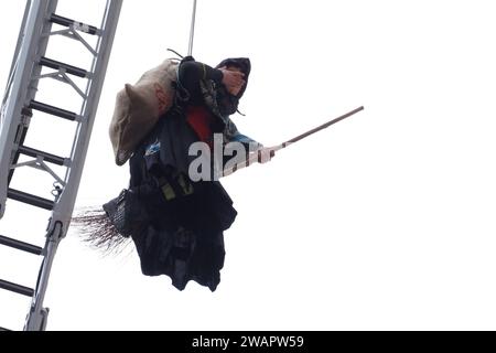 Caserta, Italien. Januar 2024. Ein als Befana getarnter Feuerwehrmann senkt sich von der Fassade des Königspalastes von Caserta ab und schenkt allen Kindern Süßigkeiten und Bonbons zum Abschluss der Weihnachtsfeiertage. Quelle: Vincenzo Izzo/Alamy Live News Stockfoto