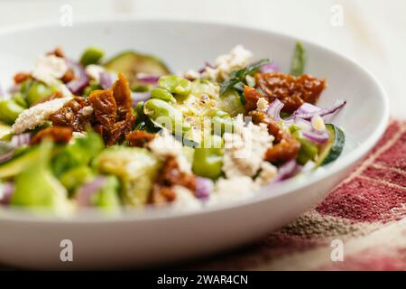 Schüssel mit hausgemachter Fava-Bohnen, Zucchini-Salat mit veganem Feta und sonnengetrockneten Tomaten. Stockfoto