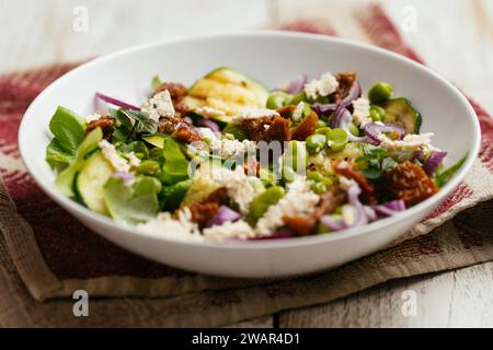 Schüssel mit hausgemachter Fava-Bohnen, Zucchini-Salat mit veganem Feta und sonnengetrockneten Tomaten. Stockfoto