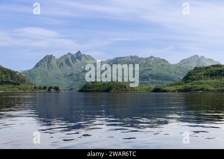 Das ruhige Fjordwasser bildet ein Spiegelbild der grünen Lofoten-Gipfel unter klarem Himmel, ein Zeugnis für die unberührte Schönheit der Arktis Stockfoto