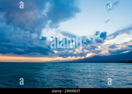 Farbenfroher Sonnenuntergang auf dem Meer. Bergsee in den Strahlen der orangen Sonne. Kirgisistan, Issyk-Kul-See. Natürlicher Hintergrund. Querformat Stockfoto