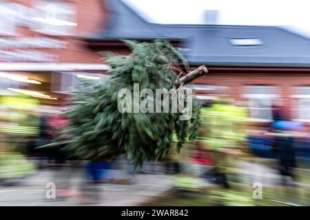 Cottbus, Deutschland. Januar 2024. Ein Baum fliegt während des traditionellen Weihnachtsbaumwurfwettbewerbs der Feuerwehr Ströbitz durch die Luft (Langbelichtungsaufnahme). Mehr als 80 Besucher nahmen am Wettbewerb im Cottbuser Stadtteil Ströbitz Teil, bei dem der Gewinner diejenige ist, die am weitesten einen Weihnachtsbaum werfen kann. Vorher konnten sie zusammen mit anderen Besuchern eine Mahlzeit genießen. Der Erlös aus der Veranstaltung wird an eine soziale Einrichtung in der Stadt Cottbus gespendet. Kredit: Frank Hammerschmidt/dpa/ZB/dpa/Alamy Live News Stockfoto