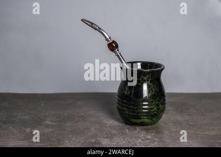 Traditionelles Bombilla-Stroh in einer schwarz-grünen Yerba Mate Tasse auf einem Betonzementtisch, Platz für Text Stockfoto