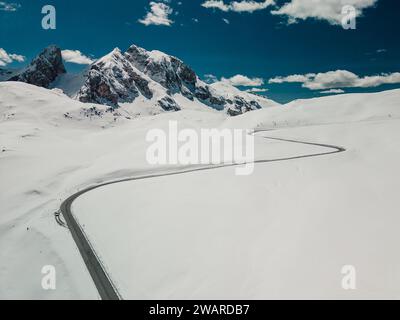 Dieses hochauflösende Bild zeigt eine malerische Winterlandschaft mit schneebedeckten Bergen und einer gewundenen Straße Stockfoto