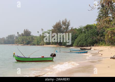 Zwei kleine grüne Ruderboote ruhen am Ufer eines ruhigen Strandes, mit blauen Meereswellen im Hintergrund Stockfoto