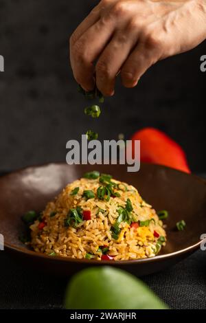 Geben Sie die letzten Zutaten von Hand in ein peruanisches Gericht namens Arroz chaufa. Stockfoto