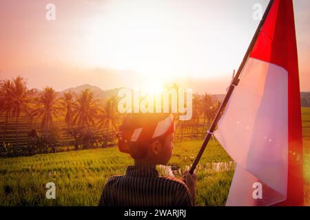 Asiatischer Teenager in traditioneller javanischer Kleidung mit indonesischer Flagge und optischem Flair Stockfoto