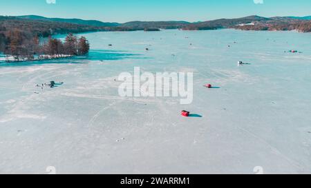 Eine Gruppe von Menschen nimmt an einem Wintersport Teil, während sie über die Oberfläche eines gefrorenen Sees, umgeben von schneebedeckten Bergen, Ski fahren Stockfoto