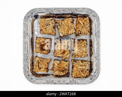 Eine köstliche Auswahl an Brownies mit goldenen Mandelflocken, bereit, im Mund zu schmelzen. Präsentiert auf Metallplatte isoliert auf weißem Hintergrund. Stockfoto
