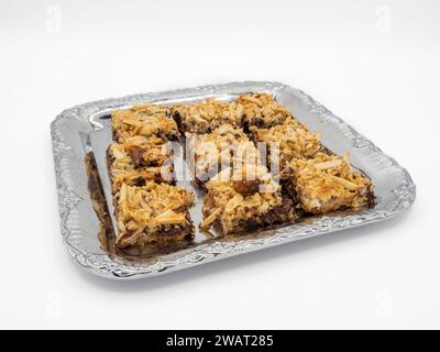 Eine köstliche Auswahl an Brownies mit goldenen Mandelflocken, bereit, im Mund zu schmelzen. Präsentiert auf Metallplatte isoliert auf weißem Hintergrund. Stockfoto