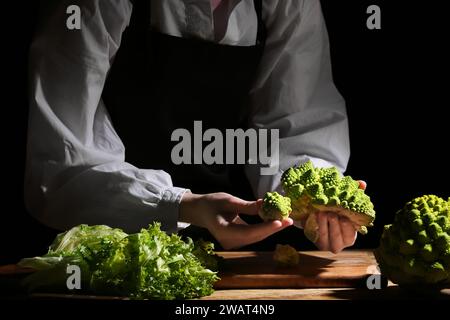 Frau mit frischem Romanesco-Brokkoli auf dunklem Hintergrund, Nahaufnahme Stockfoto