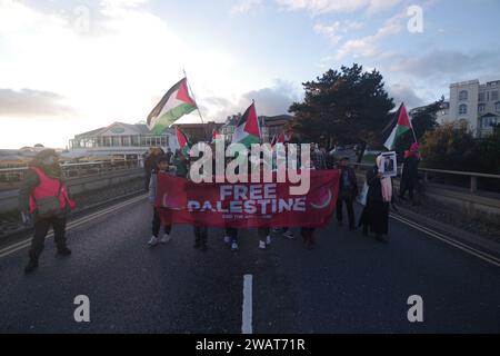 Über 200 marschierten am 6. Januar 2024 durch Bournemouth für eine Waffenruhe in Gaza. Viele in weiß gekleidet und mit Namen von Kindern, die in Gaza getötet wurden, war der marsch ein mächtiges visuelles Bild, das einen Waffenstillstand in Gaza forderte. Der marsch blockierte die Pier Approach Road, wo Rauchfackeln angezündet wurden. Der marsch wurde von Palestine Solidarity Bournemouth organisiert. Stockfoto