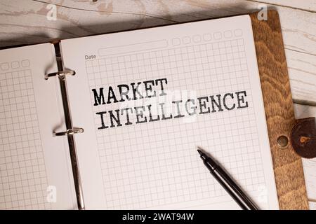 MARKET INTELLIGENCE Text auf einem Sticky mit Stift auf hölzernem Hintergrund. Stockfoto