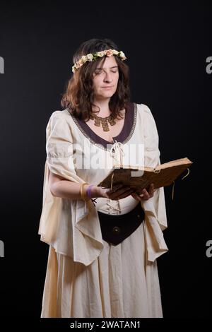 Porträt einer schönen Frau in mittelalterlicher Kleidung, die ein antikes Buch liest. Magische Geschichte. Mittelalterliche Prinzessin. Stockfoto