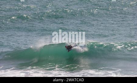 Boarder, der den Break in Kynance Cove, Cornwall, schnappt. Von der Spitze der Welle Stockfoto