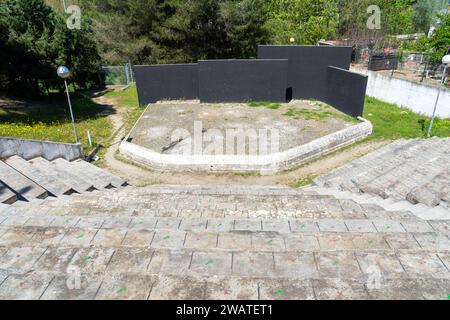 Leeres Amphitheater mit Zementsitzen und schwarzem Bühnenhintergrund im Friedens- und Freundschaftspark in der Stadt Barreiro. Stockfoto