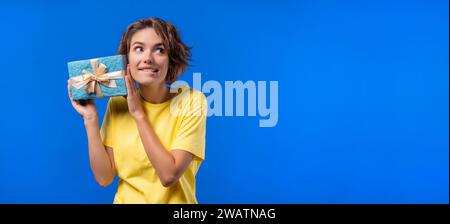 Alles Gute zum Geburtstag Frau mit Geschenkbox auf blauem Hintergrund. Mädchen lächelnd Kopierraum. Stockfoto