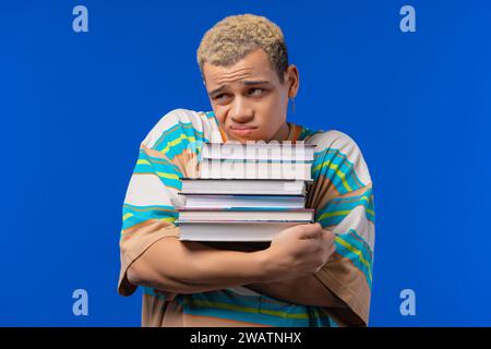 Der faule Mann Student ist unzufrieden mit vielen Büchern, Hausaufgaben in der High School Stockfoto