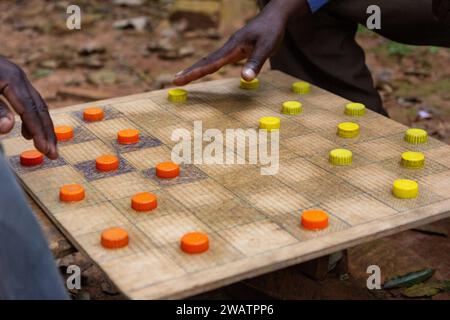 Ugandische Männer spielen Entwürfe (Checker) mit Kunststoff Flasche Kappen als Stücke dienen. Stockfoto