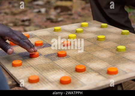 Ugandische Männer spielen Entwürfe (Checker) mit Kunststoff Flasche Kappen als Stücke dienen. Stockfoto