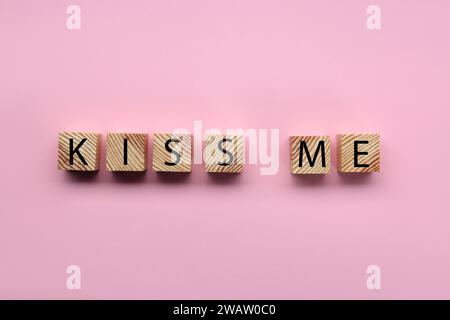 Holzwürfel mit Phrase Kiss mich auf rosa Hintergrund, flach Stockfoto