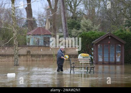 Grantchester, Großbritannien. Januar 2024. Ein Bewohner von Watvögeln windet ein elektrisches Verlängerungskabel, das von Hochwasser umgeben ist, während der Fluss Great Ouse bei Granchester seine Ufer platzt. Hochwasserwarnmeldungen bleiben bestehen, da die Gewässer im Osten Englands nach Sturm Henk weiter steigen. Die wichtigsten Flüsse der Fluss Great Ouse und der Fluss Nene sind über ihre Ufer geplatzt und in die umliegende Landschaft gespült, und mit voll ausgelasteten Abflüssen werden sie wieder in Wohngebieten eingesetzt. Quelle: SOPA Images Limited/Alamy Live News Stockfoto