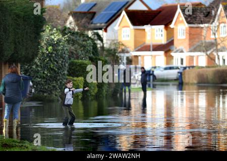 Brampton, Großbritannien. Januar 2024. Ein Junge paddelt gern im Hochwasser auf Centenary Way, während der Fluss Great Ouse bei Brampton seine Ufer sprengt. Hochwasserwarnmeldungen bleiben bestehen, da die Gewässer im Osten Englands nach Sturm Henk weiter steigen. Die wichtigsten Flüsse der Fluss Great Ouse und der Fluss Nene sind über ihre Ufer geplatzt und in die umliegende Landschaft gespült, und mit voll ausgelasteten Abflüssen werden sie wieder in Wohngebieten eingesetzt. Quelle: SOPA Images Limited/Alamy Live News Stockfoto