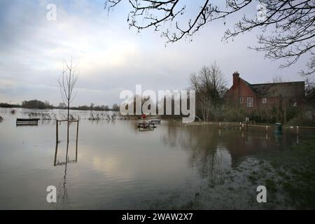 Huntingdon, Großbritannien. Januar 2024. Das Wasser erstreckt sich über einen Parkplatz und einen Fußweg und umgibt Bänke und Picknicktische, während der Fluss Great Ouse bei Hartford seine Ufer sprengt. Hochwasserwarnmeldungen bleiben bestehen, da die Gewässer im Osten Englands nach Sturm Henk weiter steigen. Die wichtigsten Flüsse der Fluss Great Ouse und der Fluss Nene sind über ihre Ufer geplatzt und in die umliegende Landschaft gespült, und mit voll ausgelasteten Abflüssen werden sie wieder in Wohngebieten eingesetzt. (Foto von Martin Pope/SOPA Images/SIPA USA) Credit: SIPA USA/Alamy Live News Stockfoto