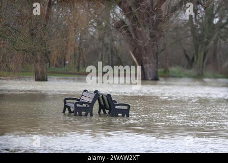 Huntingdon, Großbritannien. Januar 2024. Zwei Parkbänke lehnen sich zurück an Rücken, umgeben von Hochwasser, während der Fluss Great Ouse bei Huntingdon seine Ufer platzt. Hochwasserwarnmeldungen bleiben bestehen, da die Gewässer im Osten Englands nach Sturm Henk weiter steigen. Die wichtigsten Flüsse der Fluss Great Ouse und der Fluss Nene sind über ihre Ufer geplatzt und in die umliegende Landschaft gespült, und mit voll ausgelasteten Abflüssen werden sie wieder in Wohngebieten eingesetzt. (Foto von Martin Pope/SOPA Images/SIPA USA) Credit: SIPA USA/Alamy Live News Stockfoto