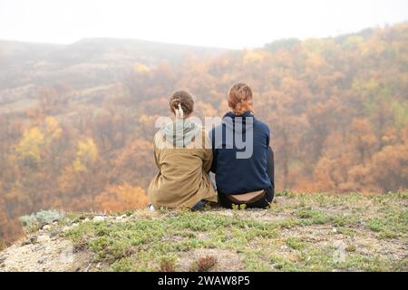 Teenagerinnen sitzen auf einem Hügel und genießen die Aussicht Stockfoto