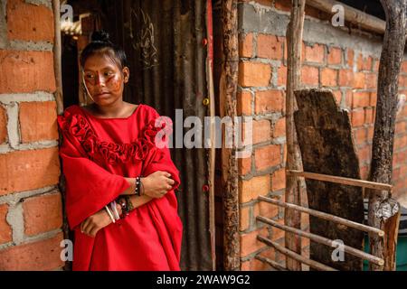 Ein Wayuu-Mädchen mit traditionellem Tuch wartet darauf, dass sie an der Reihe ist, um am traditionellen Yonna-Tanz teilzunehmen. Eine Wayuu-Gruppe von Mädchen und einem Jungen tanzen die Yonna für Touristen, die ihr Haus in Playa Camarones in La Guajira, einer Wüstenregion im Norden Kolumbiens, besuchen. Der Yonna, der traditionelle Tanz der Wayuu-Ureinwohner, wird für Feiern, für die Majayut (der Übergang von einem indigenen Mädchen zu einer Frau) oder bei Gelegenheiten im Zusammenhang mit Spiritualität aufgeführt. Frauen tragen traditionelle rote Kleider, während die Männer ein typisches Outfit namens „Wayuuco“ tragen. Stockfoto