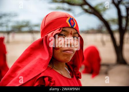 Ein Wayuu-Mädchen mit traditionellem Tuch posiert für ein Foto, während sie am traditionellen Yonna-Tanz teilnimmt. Eine Wayuu-Gruppe von Mädchen und einem Jungen tanzen die Yonna für Touristen, die ihr Haus in Playa Camarones in La Guajira, einer Wüstenregion im Norden Kolumbiens, besuchen. Der Yonna, der traditionelle Tanz der Wayuu-Ureinwohner, wird für Feiern, für die Majayut (der Übergang von einem indigenen Mädchen zu einer Frau) oder bei Gelegenheiten im Zusammenhang mit Spiritualität aufgeführt. Frauen tragen traditionelle rote Kleider, während die Männer ein typisches Outfit namens „Wayuuco“ tragen. (Foto: Antonio Cascio/SOP Stockfoto