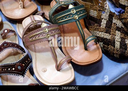 Bunte handgemachte Chappalls (Sandalen), die auf einem indischen Markt verkauft werden, handgefertigte Lederschuhe, traditionelle Schuhe. Stockfoto