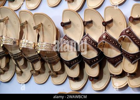 Bunte handgemachte Chappalls (Sandalen), die auf einem indischen Markt verkauft werden, handgefertigte Lederschuhe, traditionelle Schuhe. Stockfoto