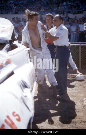 SACRAMENTO, KALIFORNIEN - AUGUST 1958: Eine Gruppe von Männern kümmert sich um den Fahrer, nachdem sein Auto während einer Autoausstellung auf der Sacramento State Fair um den August 1958 in Sacramento, Kalifornien, umgekippt und abgestürzt ist. (Foto: Hy Peskin) Stockfoto