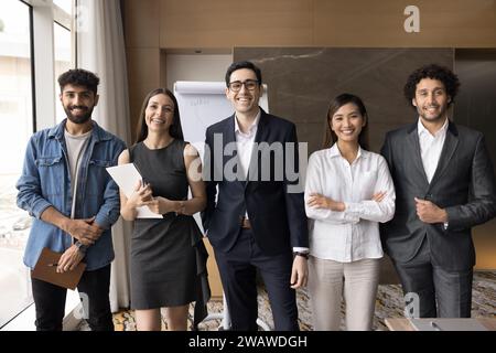 Multiethnisches Team von fröhlichen, erfolgreichen jungen Managern, die vor der Kamera lächeln Stockfoto
