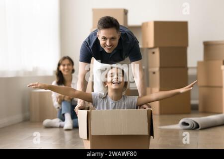 Lachender Vater, der mit glücklichem kleinen Tochter-Kind und Umzugskasten spielt Stockfoto