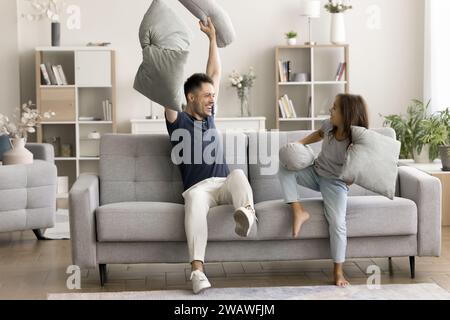 Verspielter, fröhlicher Vater und aktives Tochter-Kind kämpfen mit Kissen Stockfoto