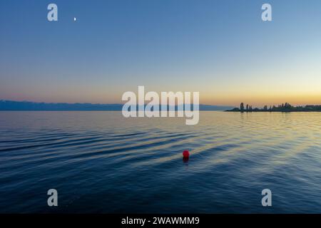 Farbenfroher Sonnenuntergang auf dem Meer. Bergsee in den Strahlen der orangen Sonne. Kirgisistan, Issyk-Kul-See. Natürlicher Hintergrund. Querformat Stockfoto