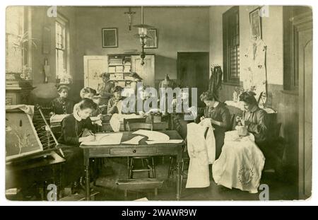 Originale edwardianische Postkarte von jungen Frauen in einem christlich-katholischen Klassenzimmer mit Nähen, Stickereien in einem Nähzimmer in einer relous School oder einem Kloster für junge Damen (es gibt einen Schrein für die Muttergottes). Die Mädchen wären in allen Aspekten des Haushalts geschult worden. Postkarte vom 1908, London, Großbritannien Stockfoto