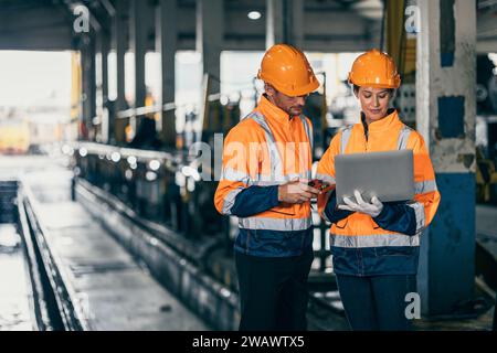 Team für Sicherheitsingenieure, die mit der Inspektion von Laptops in einer Baufabrik für Schwerindustrie zusammenarbeiten. Stockfoto