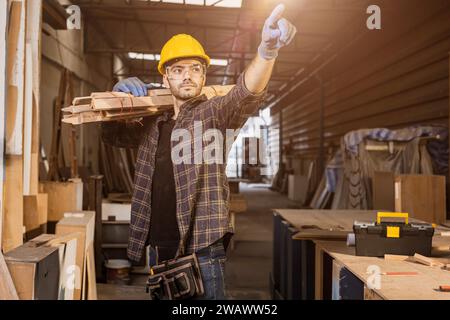 Portrait Smart Builder Holz männliche Möbelhersteller, Sägewerkarbeiter professionell stehend stark und selbstbewusst tragend Holzdielen Stockfoto