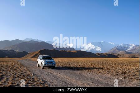 Geländefahrzeug vor schneebedeckten Bergen, Pamir Mountains mit Lenin Peak, hohe Berge, Transalai Range, Alay District, Kirgisistan Stockfoto