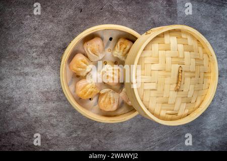 Hausgemachte Teigtaschen dimmen Nahaufnahme in einer Bambus-Dampfbox auf dem Tisch. Horizontale Draufsicht von oben Stockfoto