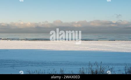 Der Winter ist mit Gold geschmückt, eine malerische Harmonie am ruhigen, verschneiten Meer. Stockfoto