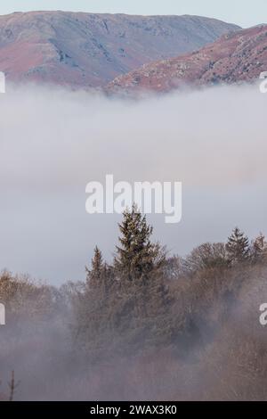 Cumbria, Großbritannien. Januar 2024. Wetter in Großbritannien. Sonnenbrand des tief liegenden Nebels über dem versteckten Lake Windermere, vom Windermere Village aus gesehen, dem Lake District. Quelle: Gordon Shoosmith/Alamy Live News Stockfoto