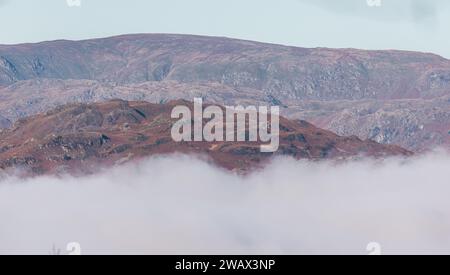 Cumbria, Großbritannien. Januar 2024. Wetter in Großbritannien. Sonnenbrand des tief liegenden Nebels über dem versteckten Lake Windermere, vom Windermere Village aus gesehen, dem Lake District. Quelle: Gordon Shoosmith/Alamy Live News Stockfoto