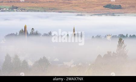 Killearn, Stirling, Schottland, Großbritannien. Januar 2024. UK Weather - eine wunderschöne Morgenwolkenumkehr über dem Dorf Stirling Killearn, von den Campsie Fells in Schottland aus gesehen. Die drei Wahrzeichen des Dorfes - das Buchanan Monument, Kirk und Village Hall, die über dem Nebel zeigen Credit: Kay Roxby/Alamy Live News Stockfoto