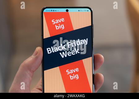 Black Friday Week mit Werbebanner und Seite aus der Amazon Shopping App auf einem Smartphone, das von einer Hand gehalten wird, UK Stockfoto