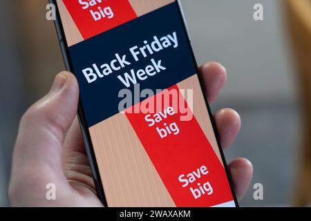 Black Friday Week mit Werbebanner und Seite aus der Amazon Shopping App auf einem Smartphone, das von einer Hand gehalten wird, UK Stockfoto